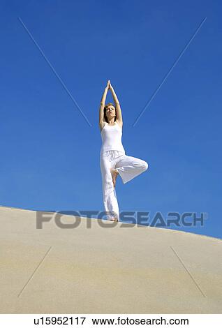 Low angle view of a young woman practicing yoga in the tree pose View Large Photo Image Stock Photo - Low angle view of a young woman practicing yoga in the tree pose. Fotosearch