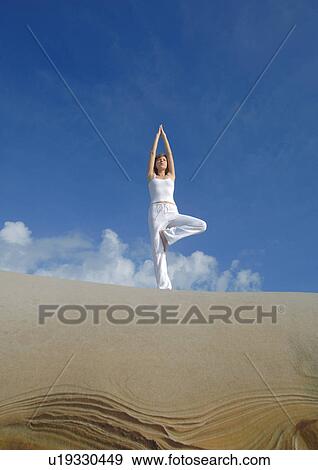 Low angle view of a young woman meditating in the tree pose View Large Photo Image Stock Photo - Low angle view of a young woman meditating in the tree pose. Fotosearch