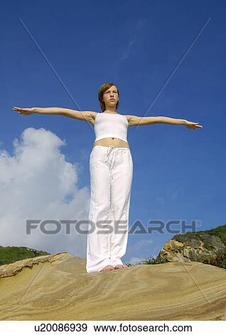 Low angle view of a young woman practicing yoga View Large Photo Image Stock Photo - Low angle view of a young woman practicing yoga. Fotosearch