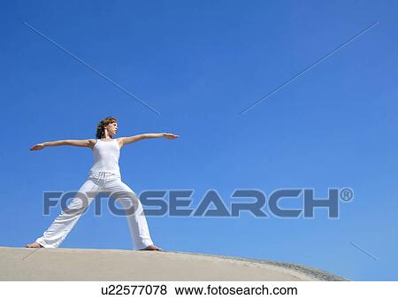 Stock Photo - Low angle view of a young woman practicing yoga. Fotosearch