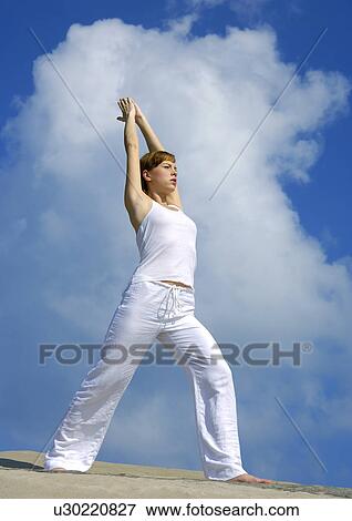 Stock Photo - Low angle view of a young woman practicing yoga. Fotosearch