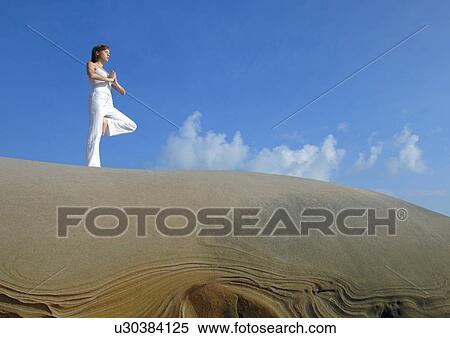 Low angle view of a young woman practicing yoga View Large Photo Image Stock Photography - Low angle view of a young woman practicing yoga. Fotosearch
