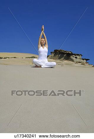 Stock Image - Young woman practicing yoga in a prayer position. Fotosearch