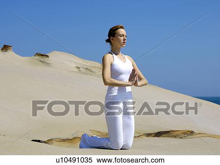 Stock Photography - Young woman practicing yoga in a prayer position. Fotosearch