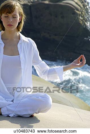 Stock Image - Young woman practicing yoga in the lotus position. Fotosearch