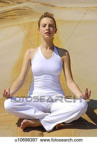Stock Photo - Young woman practicing yoga in the lotus position. Fotosearch