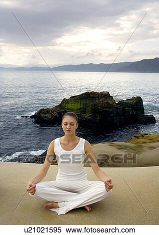 Stock Photography - Young woman practicing yoga in the lotus position. Fotosearch
