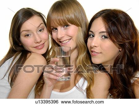 Portrait of a young woman holding a glass of water with two young women beside her View Large Photo Image Stock Photograph - Portrait of a young woman holding a glass of water with two young women beside her. Fotosearch