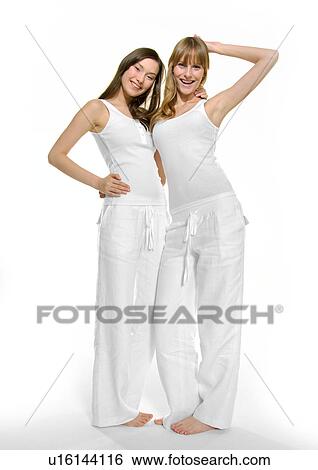 Portrait of two young women standing with their arms around and smiling View Large Photo Image Stock Photograph - Portrait of two young women standing with their arms around and smiling. Fotosearch