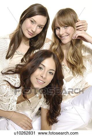 Stock Image - Portrait of three young women sitting together and smiling. Fotosearch
