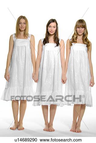 Stock Image - Portrait of three young women standing with holding each other's hands. Fotosearch