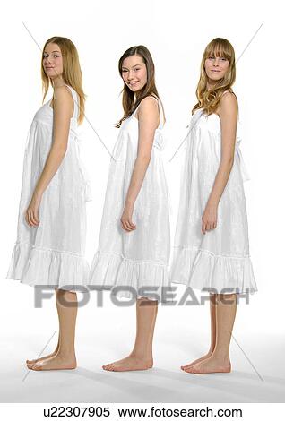 Stock Photography - Side profile of three young women standing together in a row. Fotosearch
