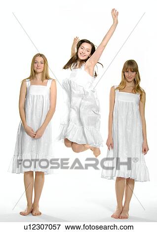 Young woman jumping with two other young women standing beside her View Large Photo Image Stock Photo - Young woman jumping with two other young women standing beside her. Fotosearch