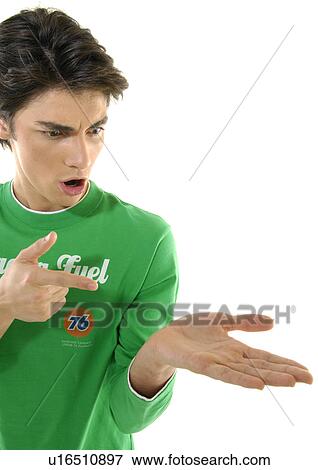 Close-up of a young man pointing towards his palm and looking shocked View Large Photo Image Stock Photo - Close-up of a young man pointing towards his palm and looking shocked. Fotosearch