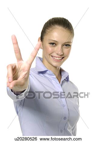 Stock Photograph - Portrait of a young woman making a peace sign and smiling. Fotosearch