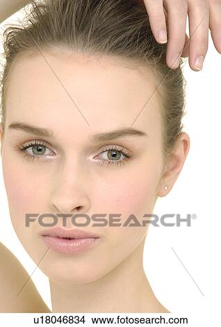 Picture - Portrait of a young woman with her hand on her head. Fotosearch