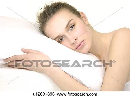 Portrait of a young woman leaning on a pillow View Large Photo Image Stock Photograph - Portrait of a young woman leaning on a pillow. Fotosearch