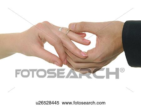 Stock Photography - Close-up of a man's hand putting the wedding ring on a woman's finger. Fotosearch
