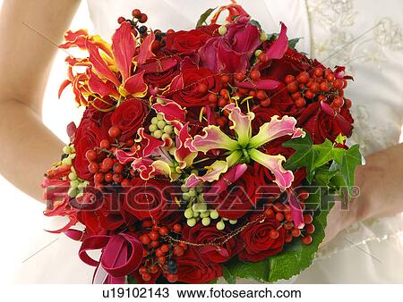 Stock Image - Mid section view of a bride holding a bouquet of flowers. Fotosearch