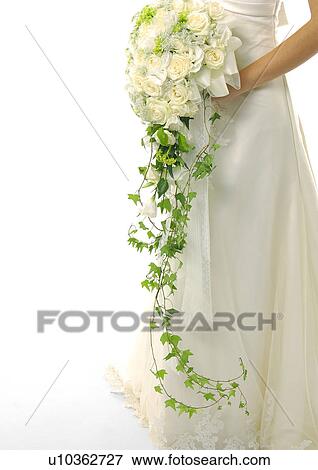 Stock Photo - Mid section view of a bride holding a bouquet of flowers. Fotosearch