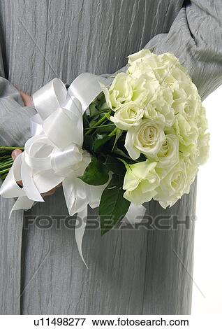 Stock Photo - Mid section view of a man holding a bouquet of flowers behind his back. Fotosearch