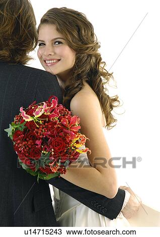 Stock Image - Portrait of a bride embracing her groom and smiling. Fotosearch
