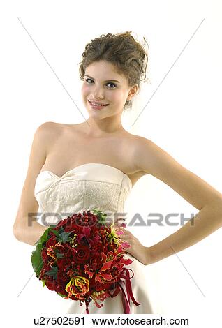 Stock Image - Portrait of a bride holding a bouquet of flowers and smiling. Fotosearch
