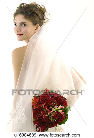 Portrait of a bride holding a bouquet of flowers behind her back View Large Photo Image Stock Photo - Portrait of a bride holding a bouquet of flowers behind her back. Fotosearch