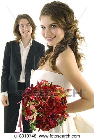 Portrait of a bride holding a bouquet of flowers with her groom standing beside her View Large Photo Image Stock Photo - Portrait of a bride holding a bouquet of flowers with her groom standing beside her. Fotosearch