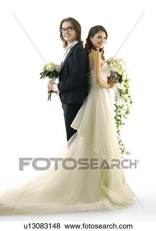 Stock Photo - Portrait of a newlywed couple standing back to back and smiling. Fotosearch