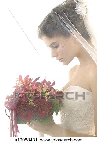 Stock Image - Side profile of a bride holding a bouquet of flowers. Fotosearch