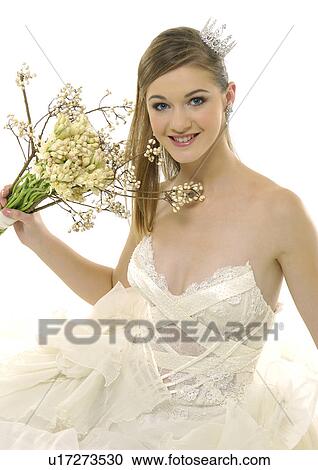 Stock Image - Portrait of a bride holding a bouquet of flowers and smiling. Fotosearch