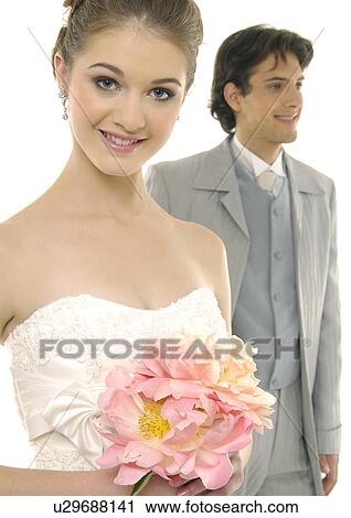 Portrait of a bride smiling with her groom standing behind her View Large Photo Image Stock Image - Portrait of a bride smiling with her groom standing behind her. Fotosearch