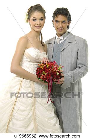 Stock Image - Portrait of a newlywed couple holding a bouquet of flowers. Fotosearch