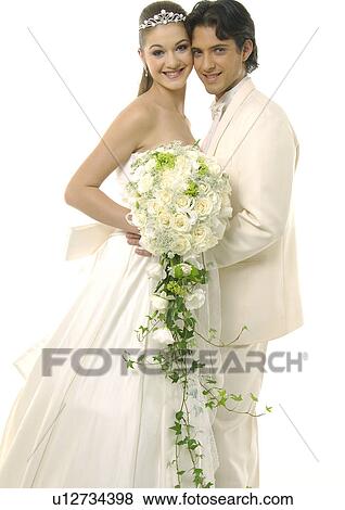 Stock Photo - Portrait of a newlywed couple smiling and holding a bouquet of flowers. Fotosearch
