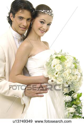 Stock Photo - Portrait of a newlywed couple smiling and holding a bouquet of flowers. Fotosearch