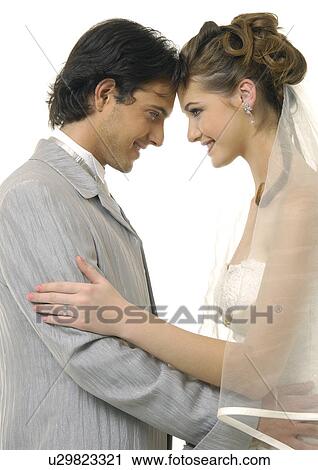 Stock Image - Side profile of a newlywed couple looking at each other and smiling. Fotosearch