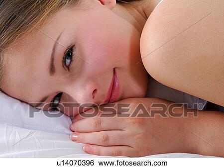 Close-up of a young woman lying on the bed and grinning View Large Photo Image Stock Photograph - Close-up of a young woman lying on the bed and grinning. Fotosearch