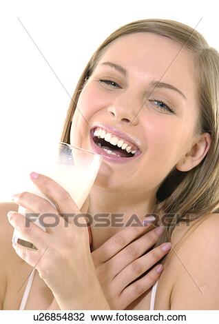Stock Image - Portrait of a young woman holding a glass of milk and laughing. Fotosearch