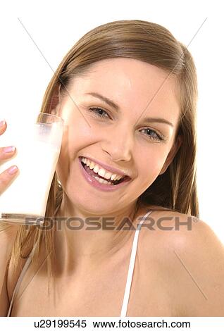 Stock Photography - Portrait of a young woman holding a glass of milk and smiling. Fotosearch