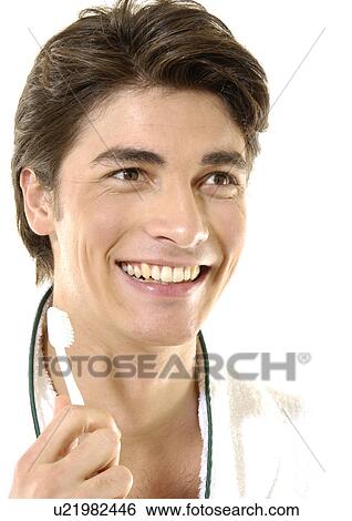 Stock Photograph - Close-up of a young man holding a toothbrush and smiling. Fotosearch