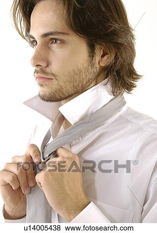 Stock Photo - Close-up of a young man tying his tie. Fotosearch