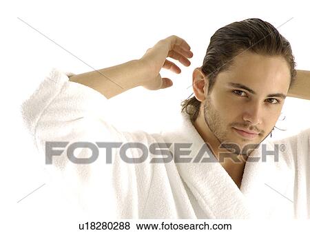 Stock Photo - Portrait of a young man adjusting his hair. Fotosearch