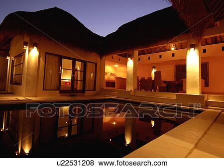 Swimming pool and a house lit up at night View Large Photo Image Stock Photo - Swimming pool and a house lit up at night. Fotosearch