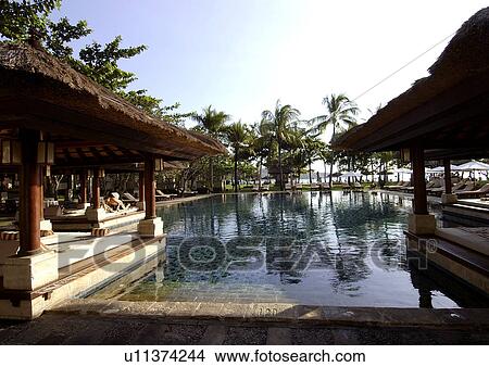 Picture - View of a pool with shades in a resort.. Fotosearch