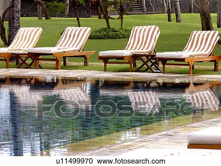 View of deck chairs by a swimming pool. View Large Photo Image Stock Image - View of deck chairs by a swimming pool.. Fotosearch