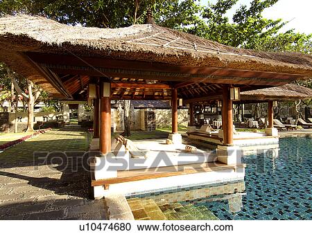 View of thatched shades by the poolside in a resort View Large Photo Image Stock Image - View of thatched shades by the poolside in a resort. Fotosearch