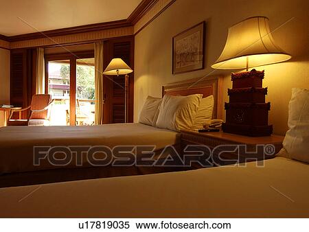 View of two single beds in a lit bedroom View Large Photo Image Stock Photography - View of two single beds in a lit bedroom. Fotosearch