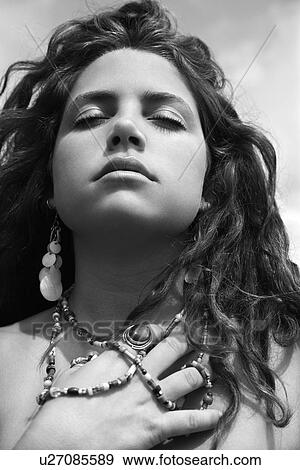 Stock Photo - Young adult Caucasian female holding necklace with closed eyes.. Fotosearch