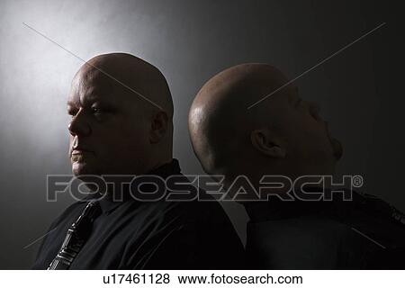 Stock Photo - Bald identical twin men standing back to back. Fotosearch